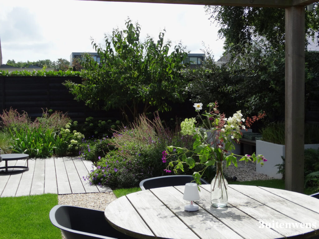 Buitenwens Tuinontwerp Heemkserk Moderne Leeftuin Heiloo met Houten eettafel en terras van hout